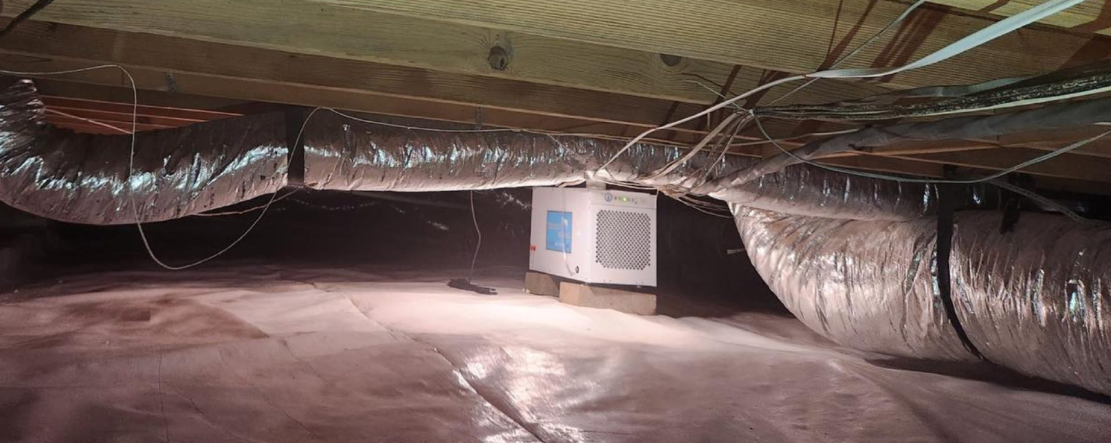 Panoramic photo of crawl space that has been encapsulated and has a dehumidifier in the enter to prevent moisture from damaging the structure or allowing mold/fungus growth.