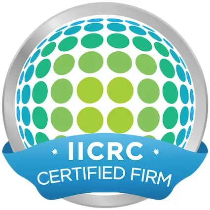 Badge: IICRC Certified Firm. Institute of Inspection, Cleaning and Restoration Certification. Silver circle with blue and green dots arranged in a sphere shape inside. A blue banner with white text arcs across the bottom.